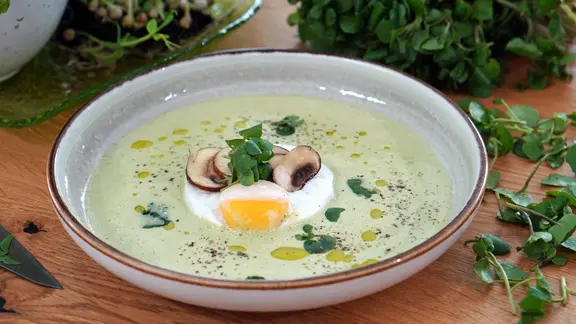 Brunnenkresse-Suppe mit pochiertem Ei auf einem Teller serviert