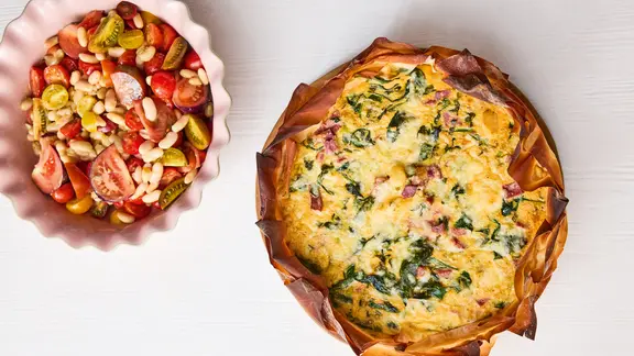 Eine gebackene Quiche und ein Tomaten-Bohnen-Salat in einer Schüssel