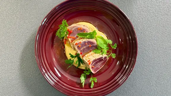 Sashimi vom Thunfisch mit Kichererbsenpüree auf einem rustikalen Teller angerichtet